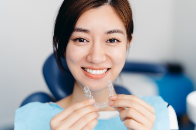 woman smiling holding invisable aligners